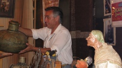 Jorge Bojanich acomoda su puesto bajo la atenta mirada de una anciana de cerámica, creada por el alfarero Carlos Moreyra
